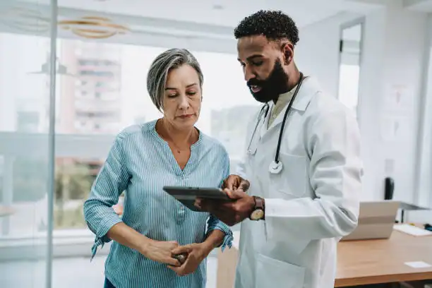 Doctor explaining health info to elderly woman with tablet, promoting digital health for seniors.